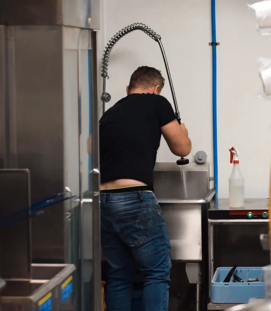 Restaurant kitchen employee is washing dishes